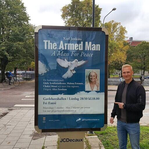 Emanuel Golabiewski framför stadstavlan för The Armed Man: A Mass For Peace med Malena Ernman m.fl.